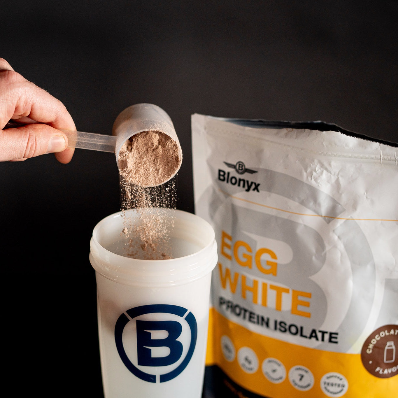 Scooping Blonyx Egg White Protein Isolate into a shaker bottle