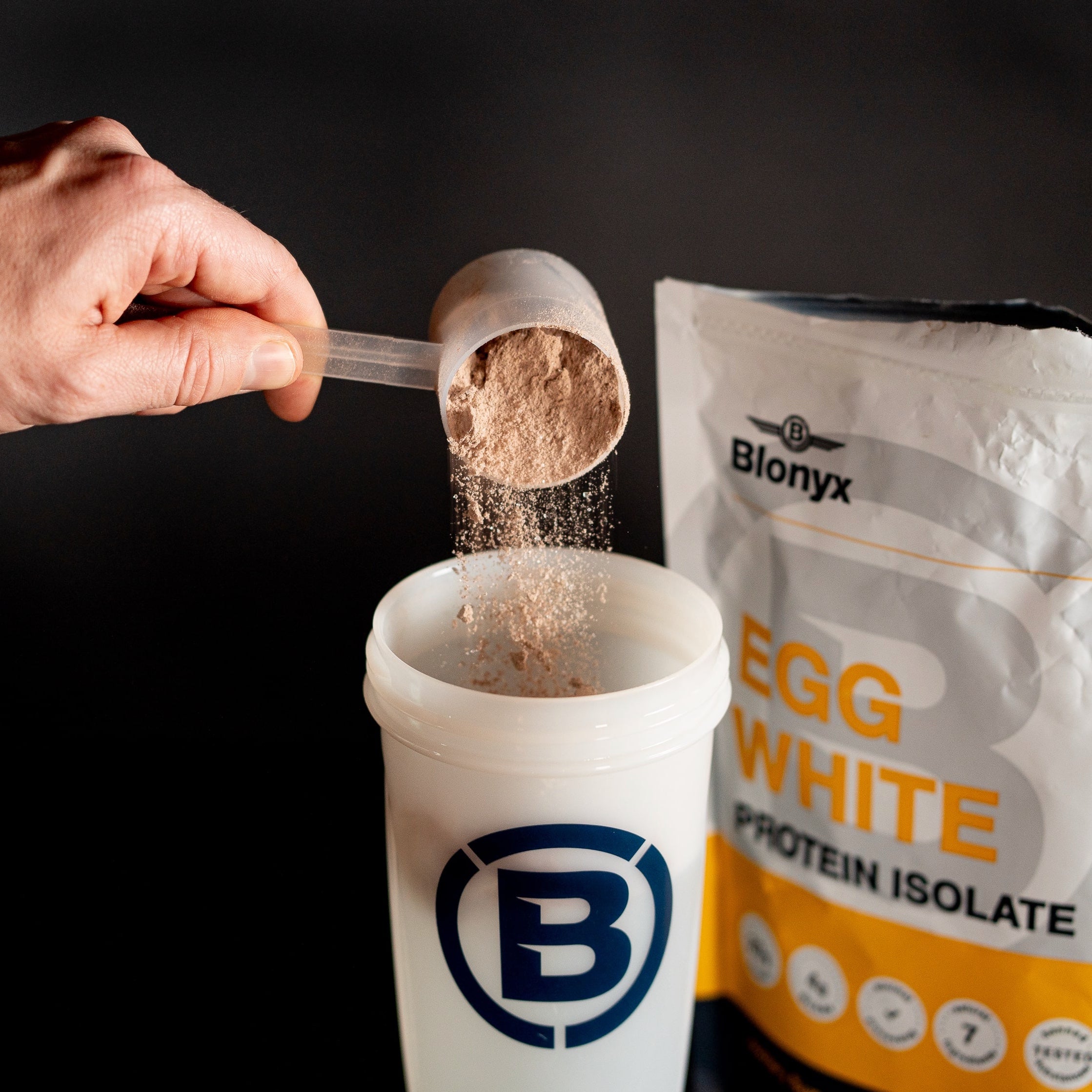 Scooping Blonyx Egg White Protein Isolate into a shaker bottle