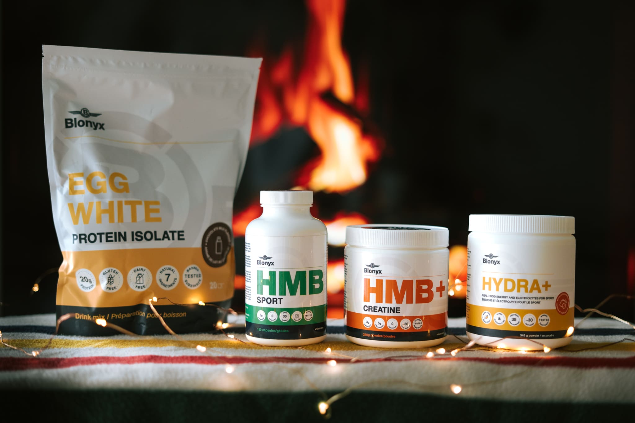 Blonyx Egg White Protein Isolate, HMB Sport, HMB+ Creatine, and Hydra+ in front of a Yule Log