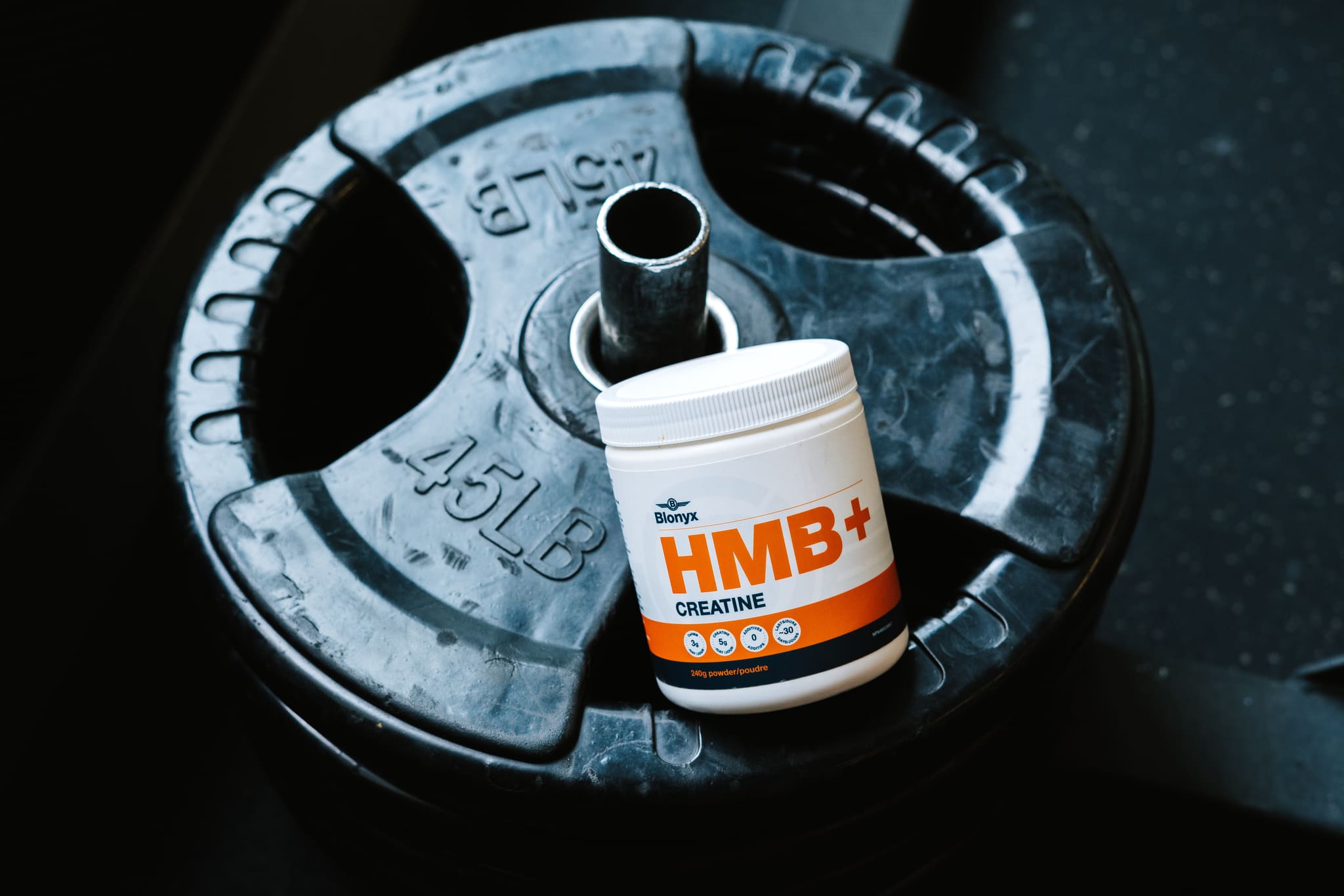 Close-up of HMB+ Creatine on gym weight plates