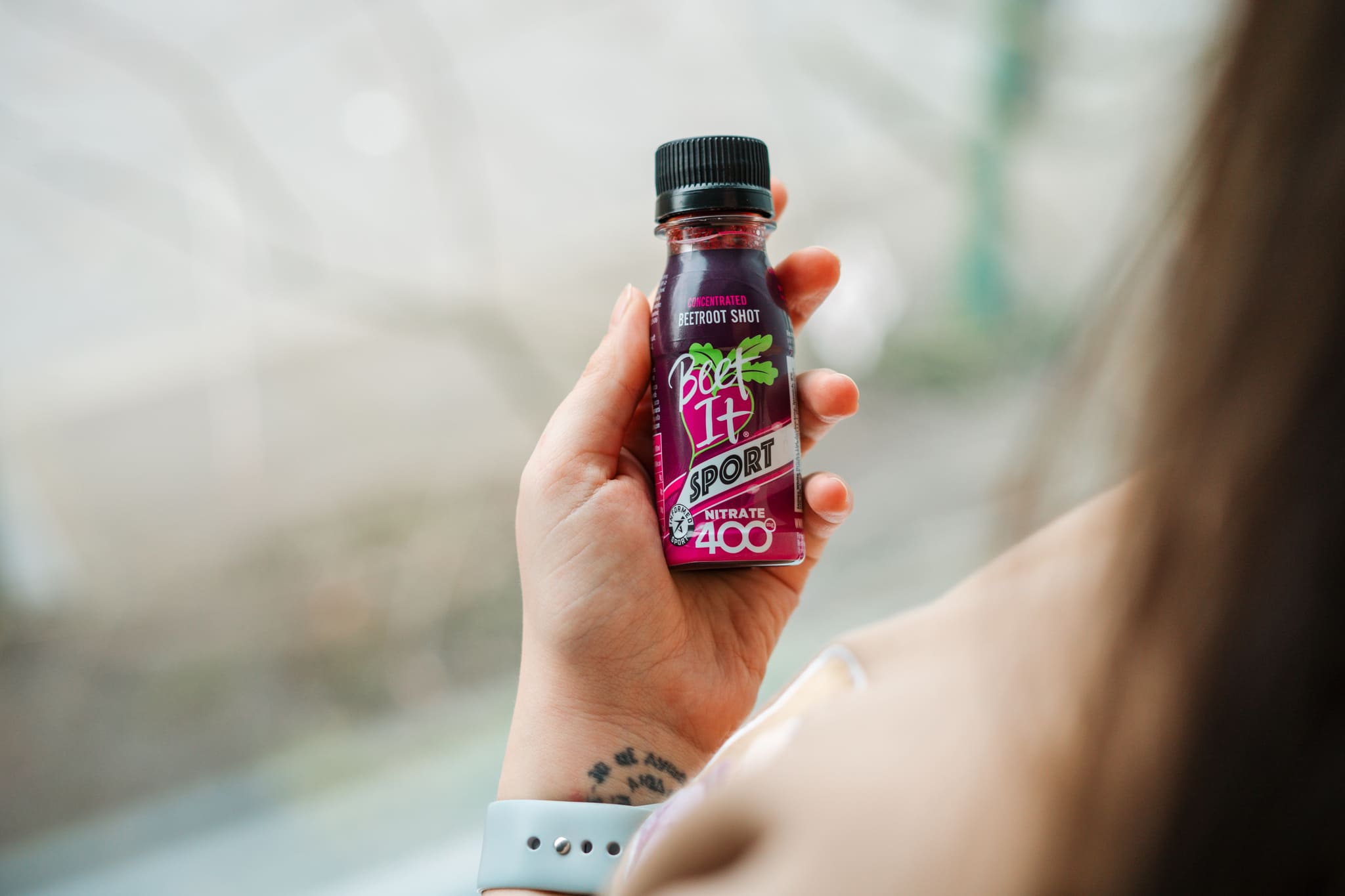 A female hand holding a Beet It Sport nitrate shot bottle.