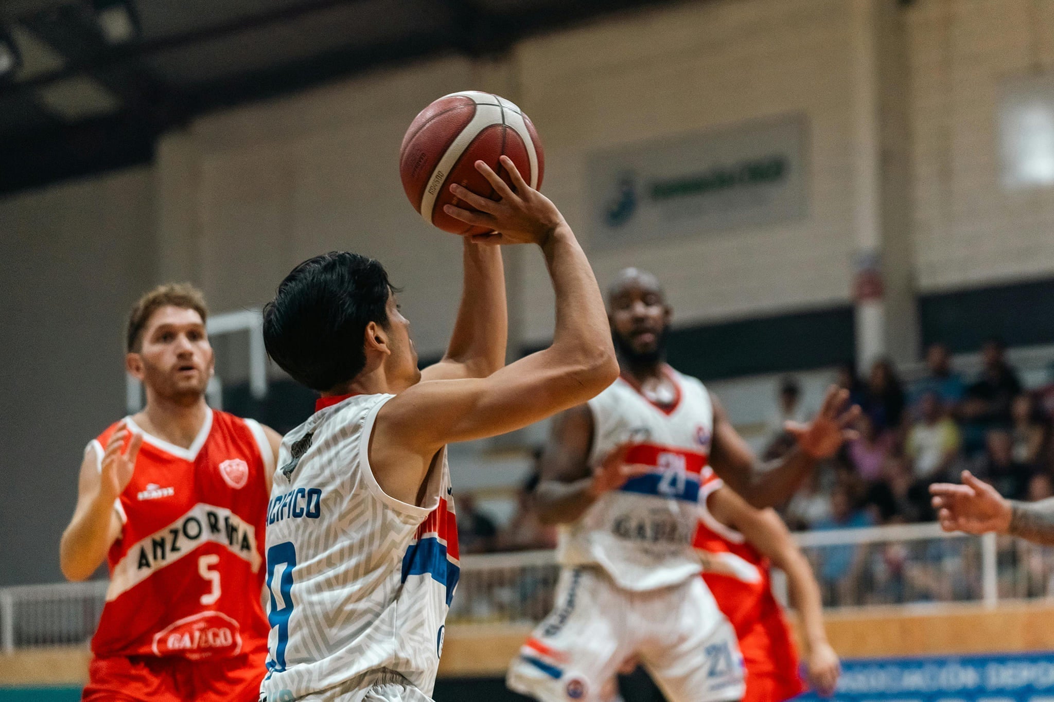 A basketball player prepares to shoot while defenders close in during a competitive game