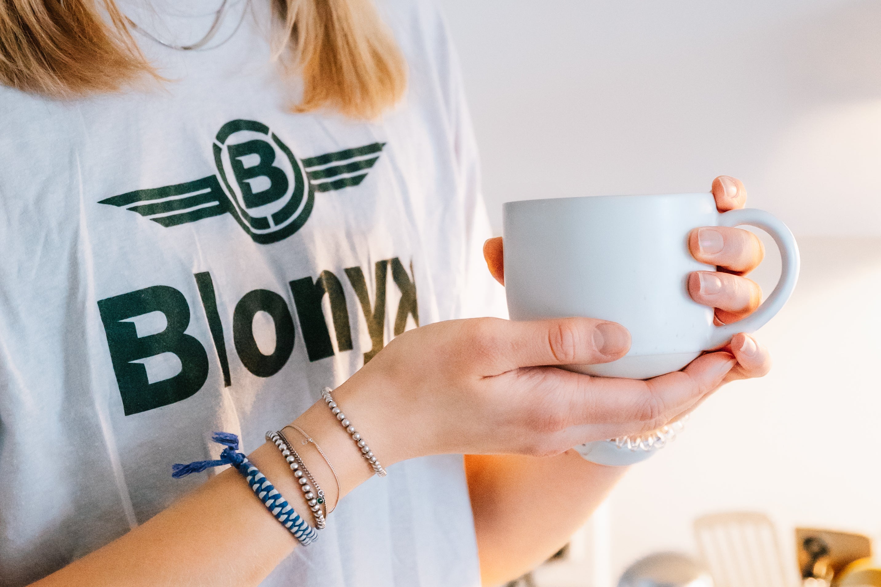 Woman holding a mug of coffee in a Blonyx shirt