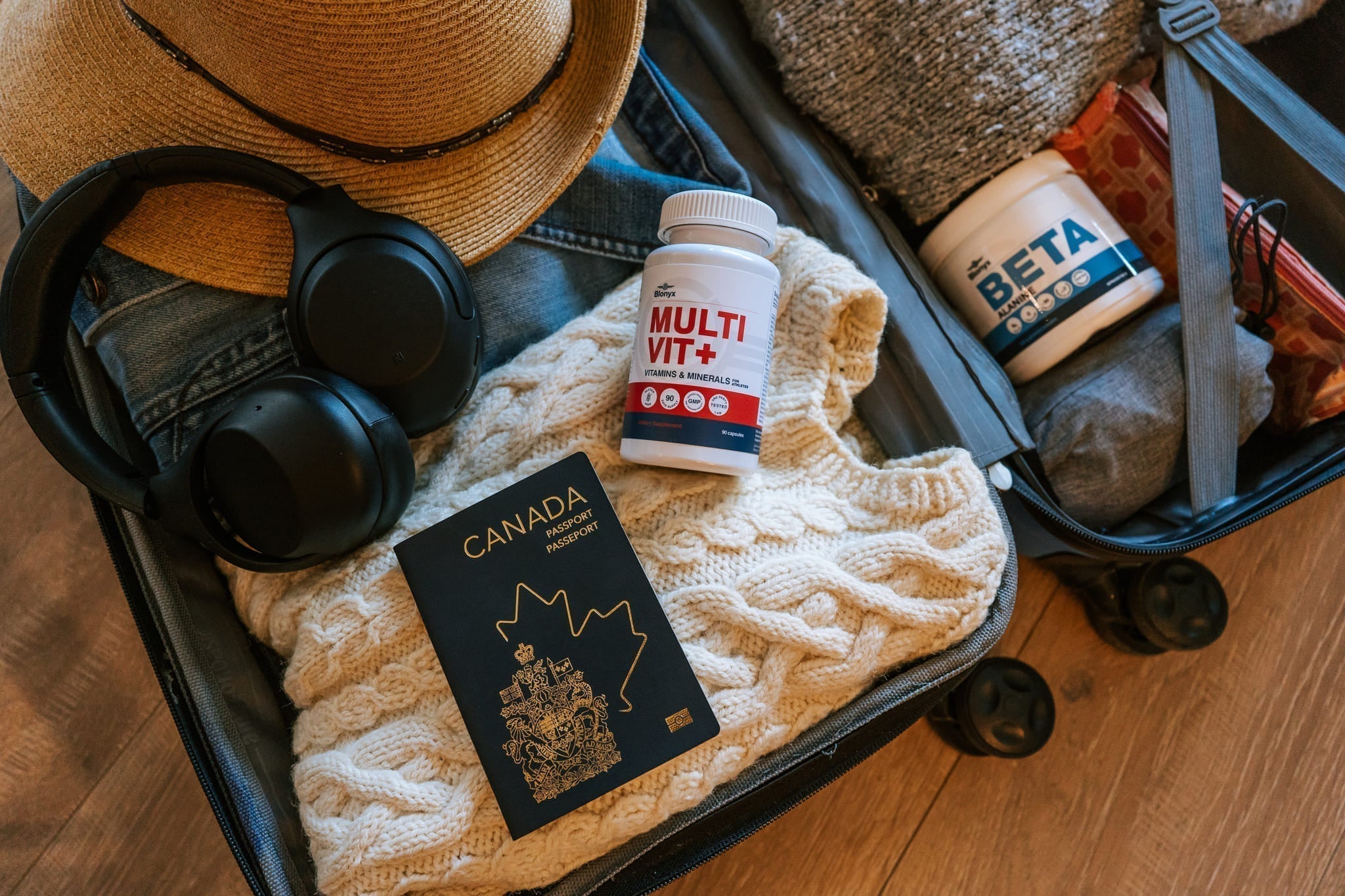 An Open Suitcase with Headphone, a Sweater, a Passport, and Blonyx Supplements