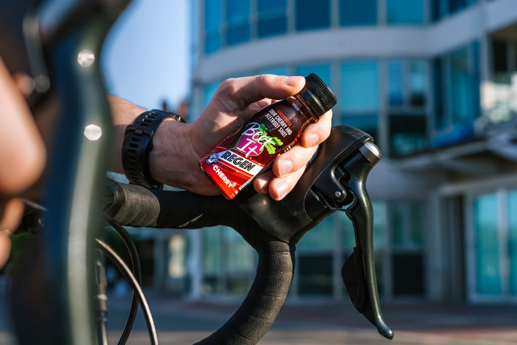Cyclist holding a Beet It Regen Cherry+ recovery shot