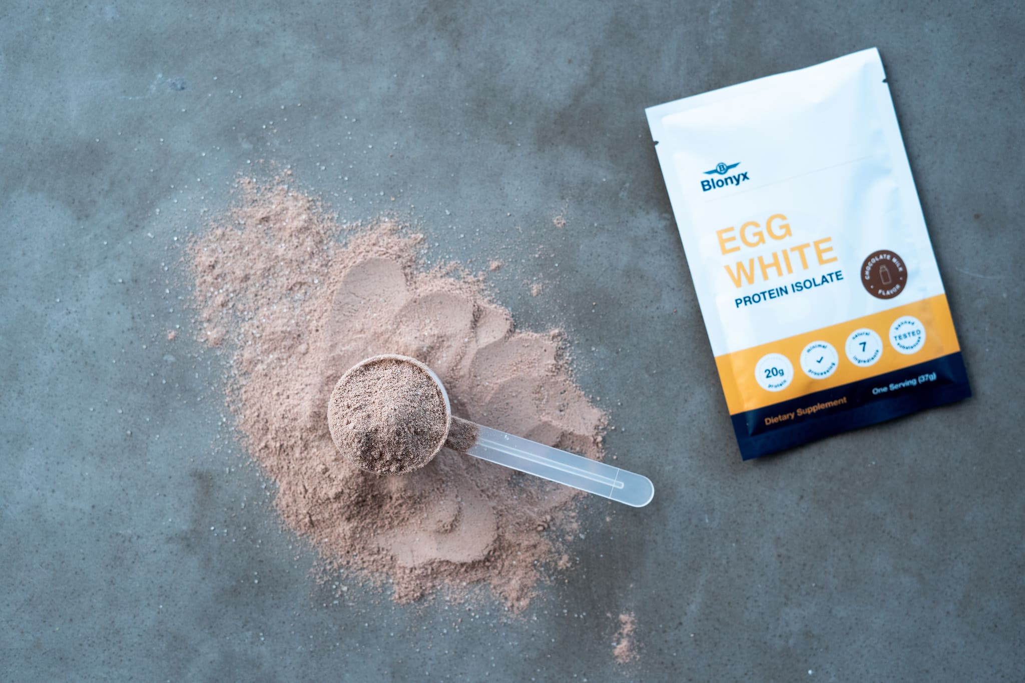 a pouch of Blonyx Egg White Protein Isolate and a scoop on a table.